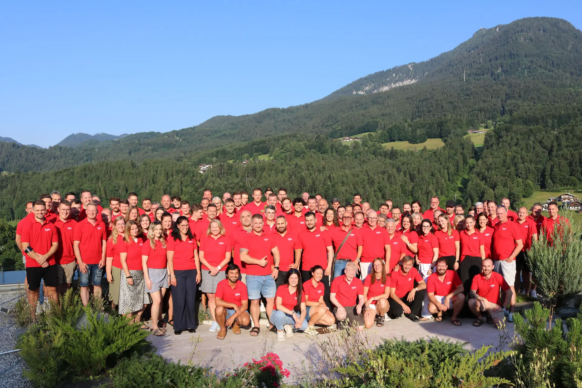 Gruppenfoto des Teams von WERNER WOHNBAU 2026 in roten Shirts vor einer Berglandschaft