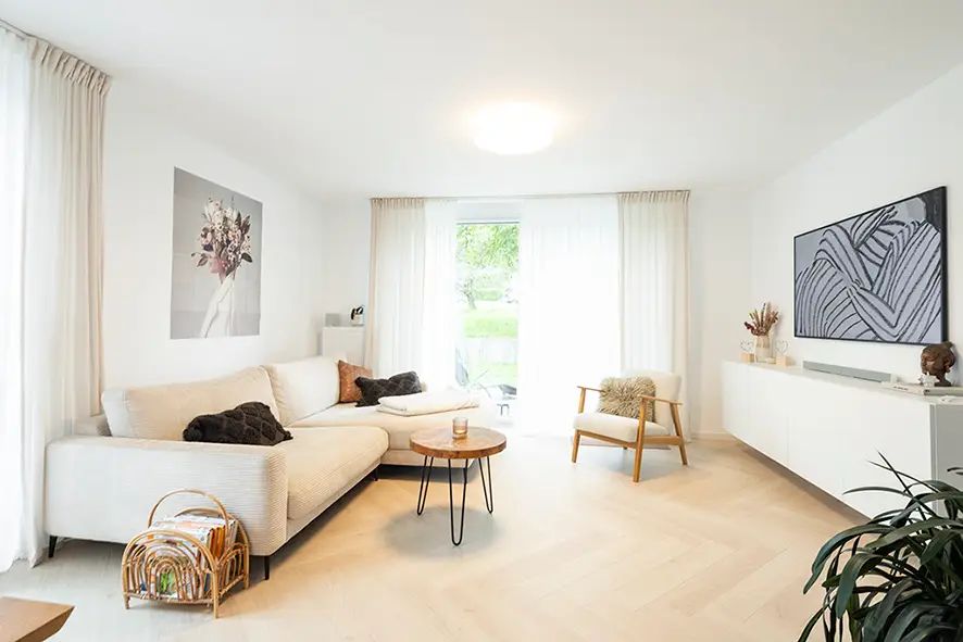 Tidy living room with white walls, a sofa, and furniture by the window
